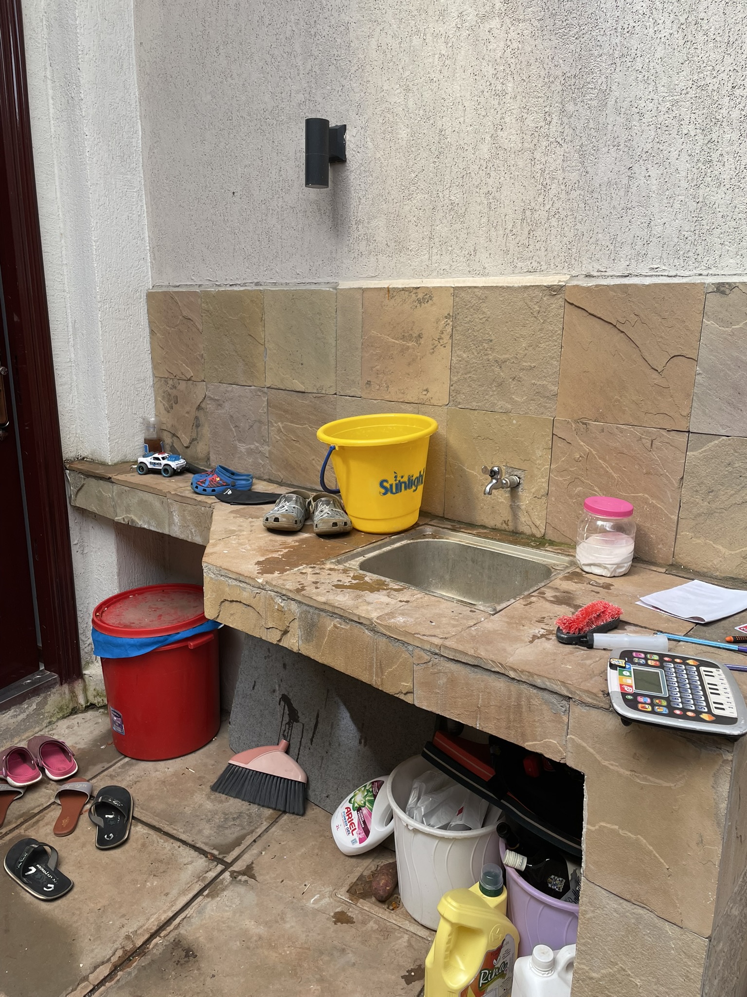 Stone utility sink station with wall-mounted tap and service counter in the exterior utility zone.